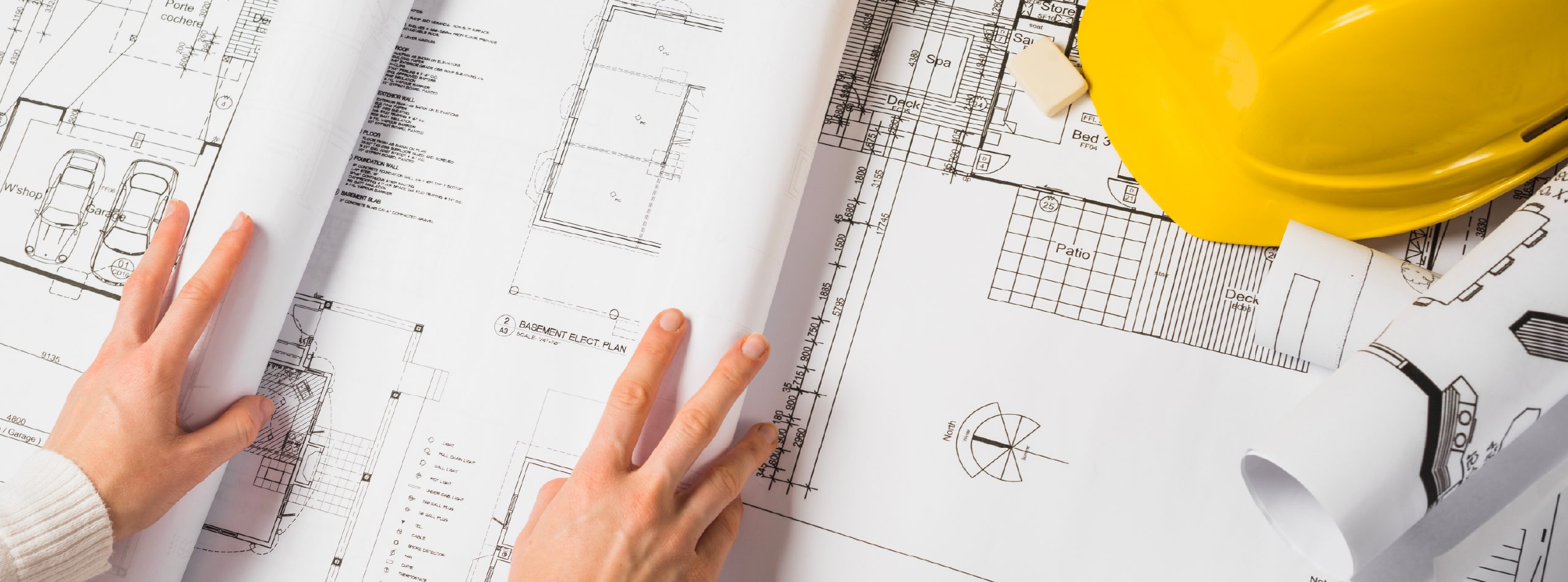 A person opening plans with a yellow hard hat
